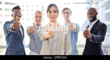 There are great rewards waiting for you at the end. Closeup shot of a group of businesspeople showing thumbs up together in an office Stock Photo