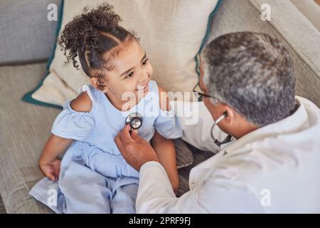 Home consultation, child and pediatrician with stethoscope doing health check on happy kid patient. Happiness, smile and young girl with medical healt Stock Photo