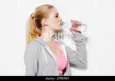 Keep hydrated. Studio shot of a young woman in exercise clothing drinking from a water bottle Stock Photo