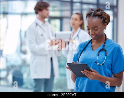 Female nurse or doctor browsing on a tablet for patient diagnosis or treatment on a medical or mobile healthcare app in a hospital. Professional gp or surgeon wearing scrubs while working in a clinic Stock Photo
