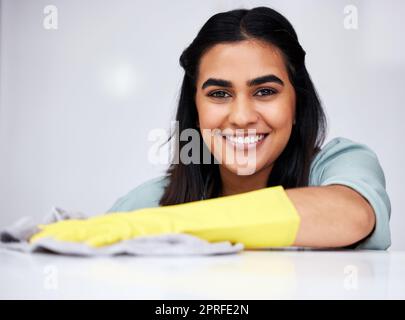 I keep all surfaces clean at all times. a woman using a cloth while wiping a white counter Stock Photo