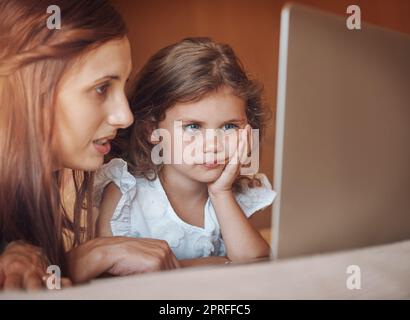Engaged with the online world. a mother and her little daughter using a laptop together at home. Stock Photo