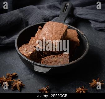 Pieces of baked brownie in a metal black frying pan on the table Stock Photo
