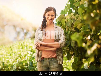 Do what you love and youll love what you do. Portrait of a cheerful young farmer posing in the fields on her farm. Stock Photo