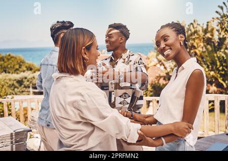 Friends, hugging and looking happy while meeting outside a restaurant. Diverse couples talking and greeting while on a double date. Friendly women and men embracing while having fun at a gathering Stock Photo