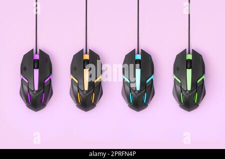 Several computer mice hang on a pastel pink background. The concept of cooperative computer video games, the use of auto-clicker and pay-per-click pla Stock Photo