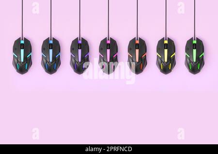 Several computer mice hang on a pastel pink background. The concept of cooperative computer video games, the use of auto-clicker and pay-per-click pla Stock Photo