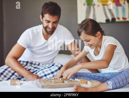 Who will win this game of x and os. a young father playing a board game with his adorable little daughter at home. Stock Photo