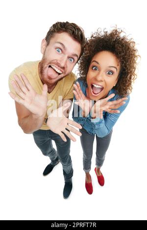 She brings out my crazy. Studio portrait of a young couple pulling faces at the camera against a white background. Stock Photo