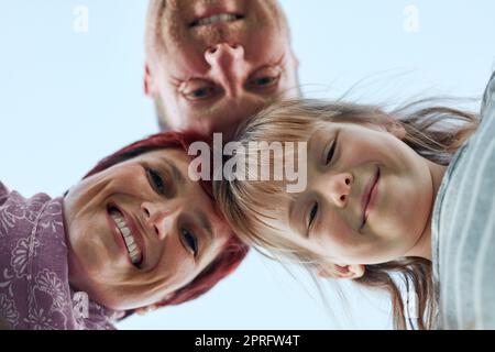 Were happy together. Low angle portrait of a cute little girl and her parents putting their heads together. Stock Photo