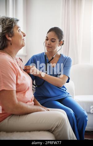 Everything sounds good to me. an attractive young female nurse examining a senior patient with a stethoscope. Stock Photo