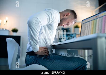 Young Businessman Having Back Pain While Sitting Stock Photo