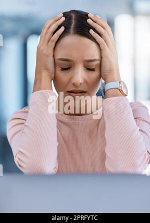 Stressed, tired and sick young woman with a headache feeling sad and overworked in an office. A frustrated, ill and unhappy female employee with a migraine suffering from pain and depression Stock Photo