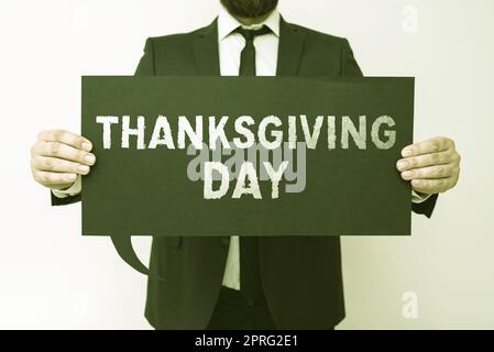 Hand writing sign Thanksgiving Day. Word for Celebrating thankfulness gratitude November holiday Man In Suit Displays With Hands Digital Signs Used For Crucial Data. Stock Photo