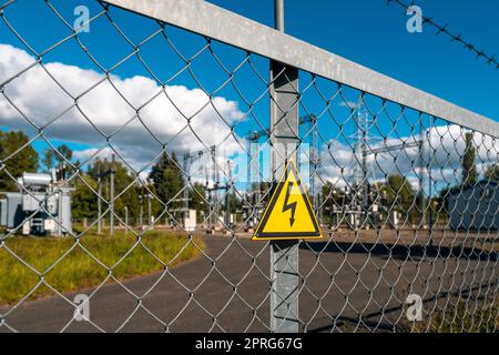 Yellow triangle with lightning behind metal mesh fence Stock Photo