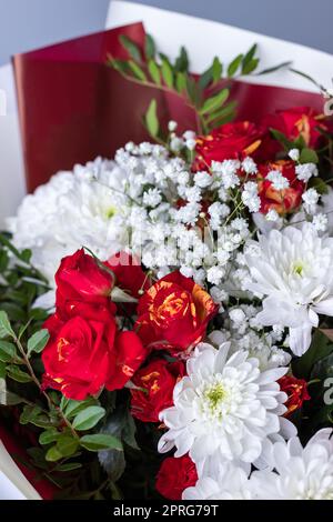 Close up bouquet of pink roses, white chrysanthemums, gypsophila and sprigs of greenery. Stock Photo