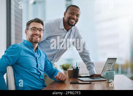 Were a great team. Portrait of two businessmen working on a laptop in their office. Stock Photo