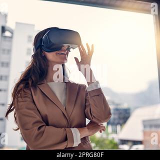 Logged into the virtual domain. a young businesswoman wearing a VR headset in an office. Stock Photo