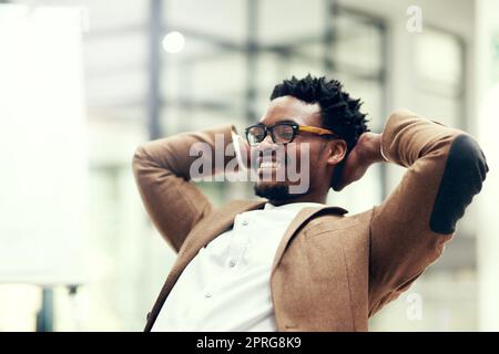 Another busy but successful day at the office. a handsome young businessman taking a break while working in an office. Stock Photo