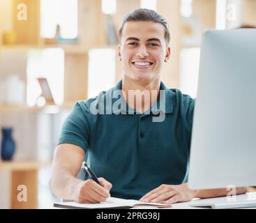 Planning, vision and motivation with business man writing notes in a book while working on a computer in a corporate office. Inspired employee on mission, researching upskill course, being proactive Stock Photo
