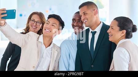 Happy business people or friends taking a selfie in the office done with work and having together. Employee team or group of colleagues taking a picture or a photo smiling after team building Stock Photo