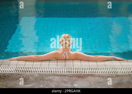 Please leave a message after the beep. Rearview shot of a woman relaxing in the pool at a spa. Stock Photo