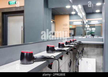 Close up of stand in washroom in gym on which are placed in row many hair dryers. Stock Photo