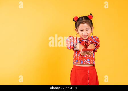 Happy Asian Chinese little girl smile wear red cheongsam handed angpao or red packet monetary gift Stock Photo