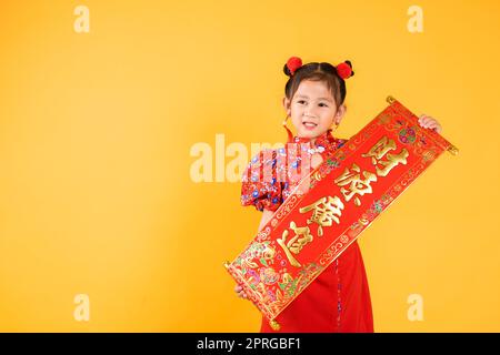 Happy Asian Chinese little child girl smile wearing red cheongsam qipao Spring festival couplets Stock Photo
