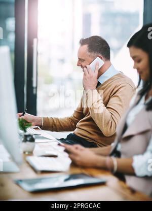 Ill meet you for lunch. a handsome mature male designer taking a call while working at his desk. Stock Photo