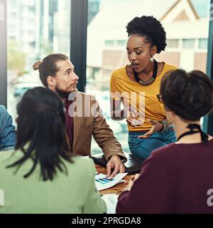 Considering everyones suggestions. a group of young creatives having a meeting in a modern office. Stock Photo
