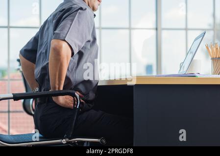 senior businessman working with laptop computer has a problem with back pain Stock Photo