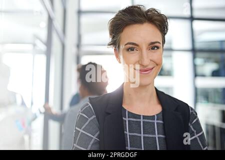 Dont dream about success - wake up and work for it. Portrait of a young businesswoman standing in an office with colleagues in the background. Stock Photo