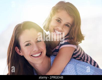 Its the little moments together that make the best memories. a mother giving her daughter a piggyback ride. Stock Photo