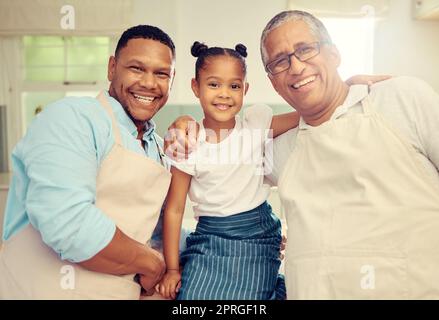 Portrait of happy family after cooking or baking in a kitchen together in a house. Father, grandpa and girl bonding with a smile, happiness and love during sweet and loving moments in kitchen Stock Photo