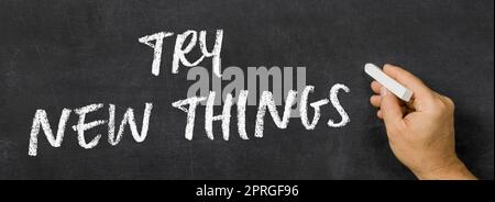 Text written on a blackboard -  Try new things Stock Photo