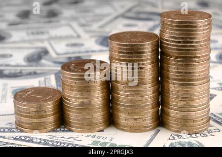 Stack of ukrainian coins in rising stacks grow up. Ukrainian money lies on US hundred dollar bills Stock Photo