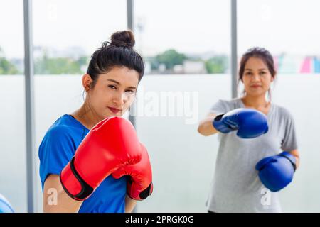 adult and young woman smiling sports fitness boxer wearing gloves practicing kick on boxing Stock Photo