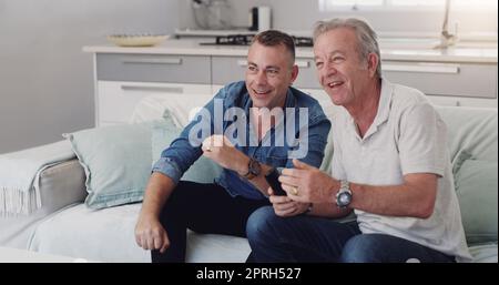 I wonder what will happen next. a father and son duo watching tv together Stock Photo