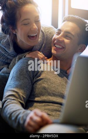 OMW thats hilarious. an affectionate young couple surfing the net while relaxing on the sofa at home. Stock Photo