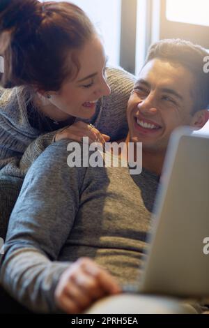 Thats amazing. an affectionate young couple surfing the net while relaxing on the sofa at home. Stock Photo