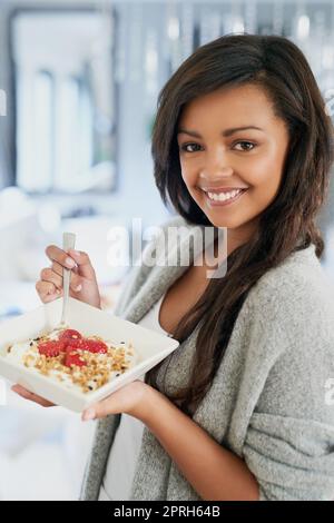 Eating healthy and feeling great. Portrait of a happy young woman enjoying a healthy breakfast at home. Stock Photo