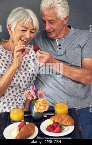 All happiness depends on a leisurely breakfast. a senior couple having breakfast in bed. Stock Photo
