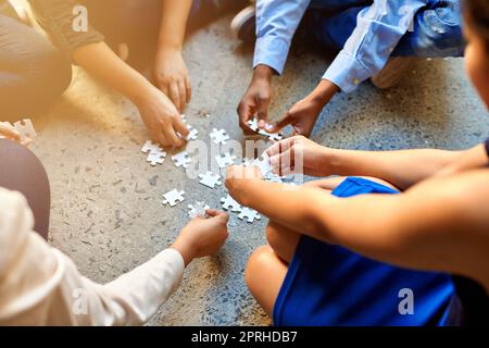 Piecing it all together. Closeup of businesspeople about to put four puzzle pieces together. Stock Photo