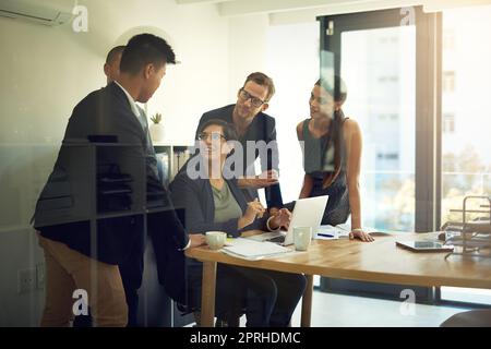 Their individual goals fit into the companys business objectives. a group of coworkers discussing something on a laptop during a meeting. Stock Photo