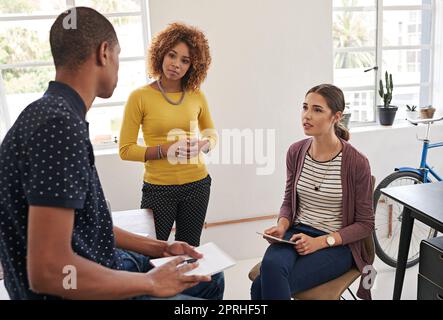 Touching base with the team. a group of colleagues having an informal meeting in a modern office. Stock Photo