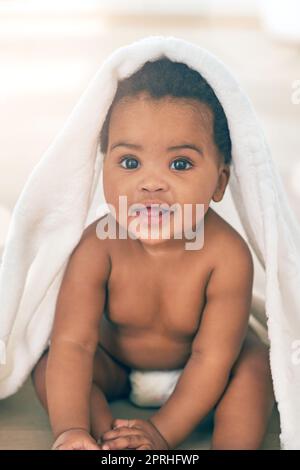 Hello little one. Portrait of an adorable baby girl covered in a towel at home. Stock Photo