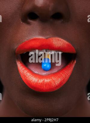 Ready for a rush. Cropped view of an african woman with bright red lips taking a pill Stock Photo