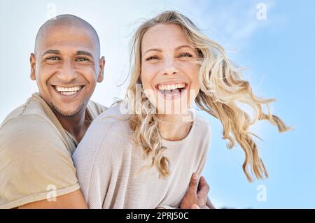 Love, blue sky and diversity couple hug, laugh and enjoy fun quality time together on travel vacation date. Happy, smile and romantic black man, woman Stock Photo