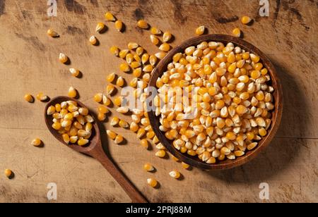 Dried corn kernels and wooden spoon in wooden bowl placed on wooden background. Stock Photo